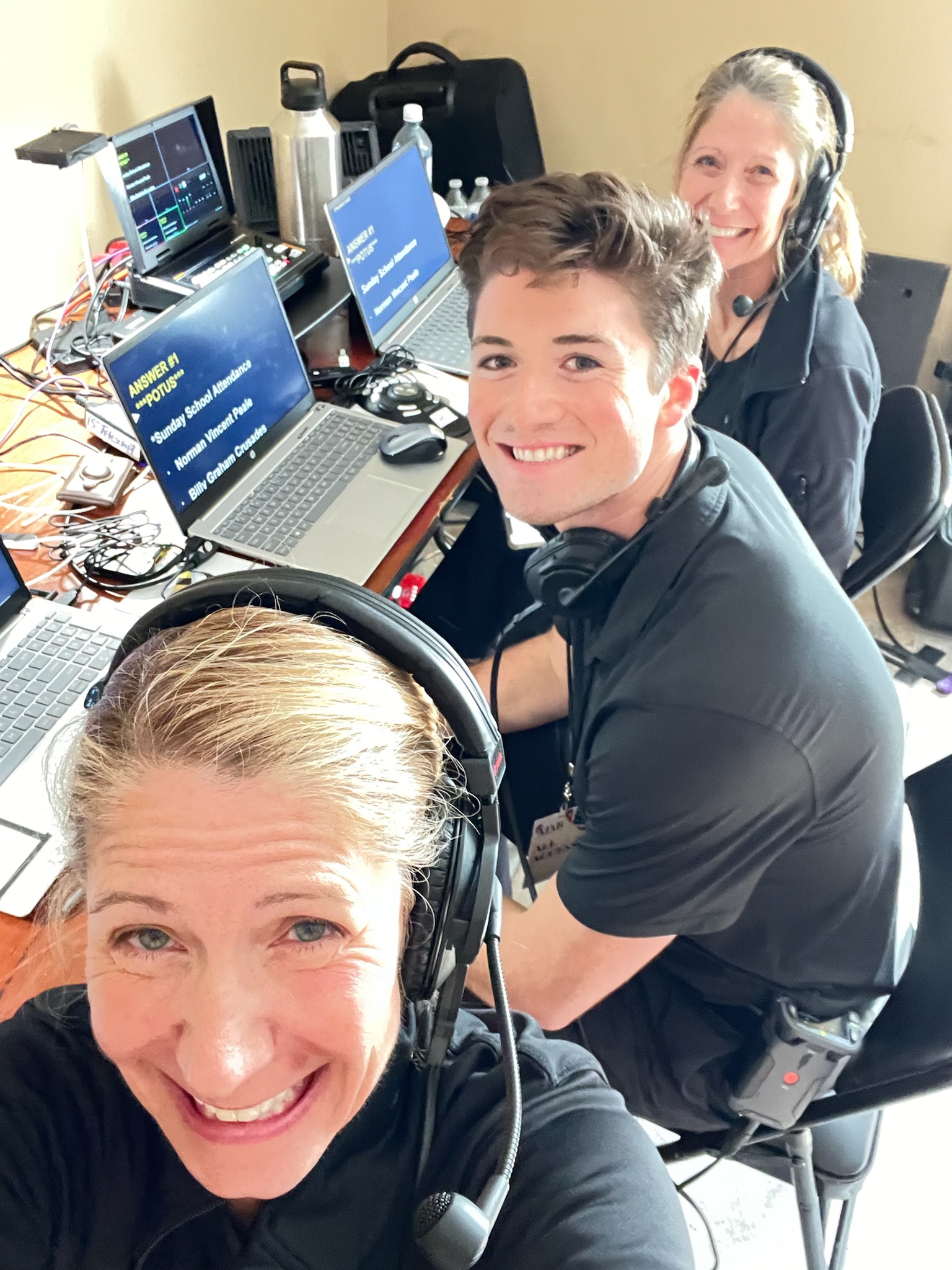Three B Prompt operators in headsets at a laptop teleprompting station