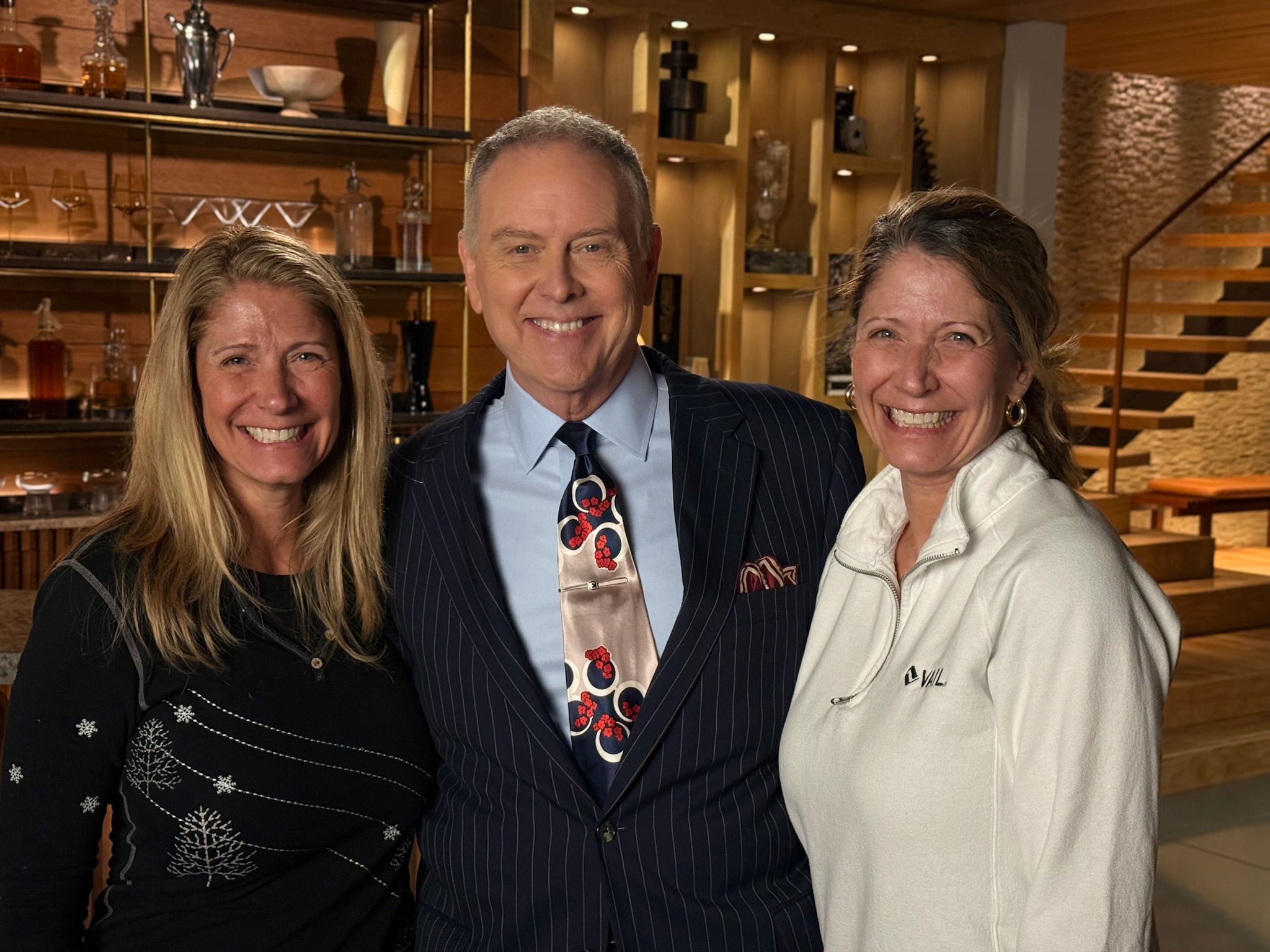 Two B Prompt operators alongside a suited on-camera host on a production set